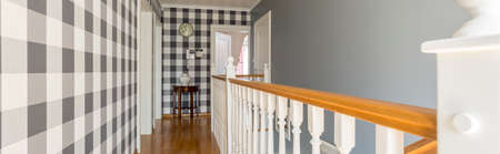 Stylish hall on the floor of a house, with checked wallpaper and wooden banisterの写真素材