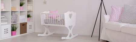 Spacious child room in white with cradle, shelving unit and sofaの写真素材
