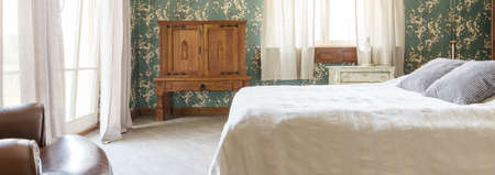 Spacious bedroom with decorative pattern wallpaper and solid wooden furniture