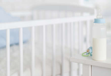 Baby bottle and dummy with crib in the backgroundの写真素材