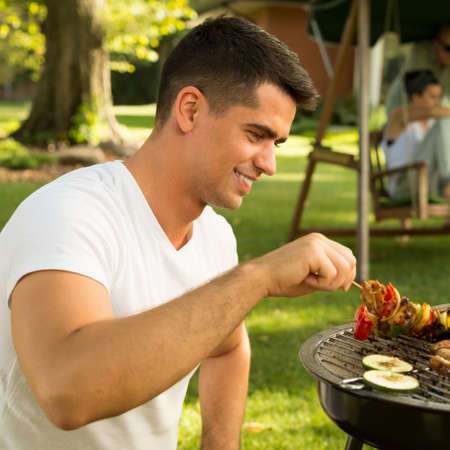 Happy handsome man making food for his friendsの写真素材
