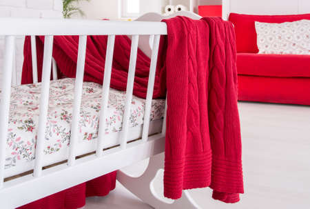 Closeup shot of a cradle with a red blanket thrown over itの写真素材