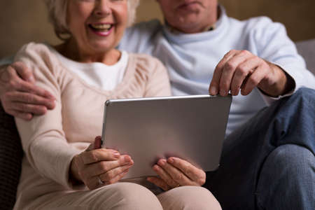 Close-up of an elderly couple sitting on a sofa and using a tabletの写真素材