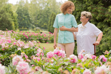 Shot of a happy elderly woman walking with her nurse around the gardenの写真素材