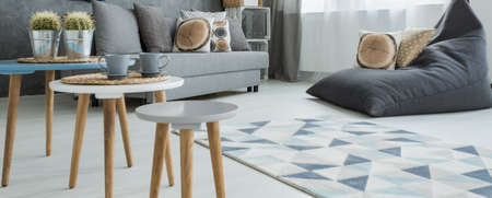 Panoramic photo of a simple but stylish apartment, with three coffee tables, a large sitting sack and a comfortable sofaの写真素材