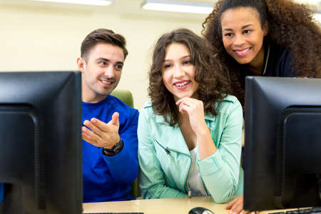 Young man shows her friends the result of working on a computer
