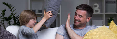 Dad and son laughing and having pillow fighting
