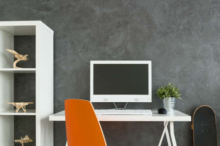 Part of room with desk and bookstand with many necessary things to work and playの写真素材