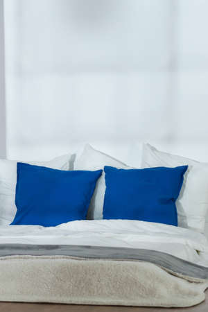 Cropped shot of bed with white and blue pillows facing the white wallの写真素材