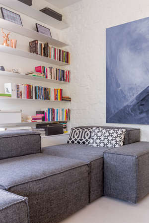 Cropped shot of a stylish room interior with bookshelves and a big painting on the wallの写真素材