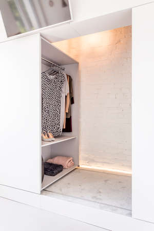 Shot of an open closet in a modern and minimalistic wardrobe with brick wallsの写真素材