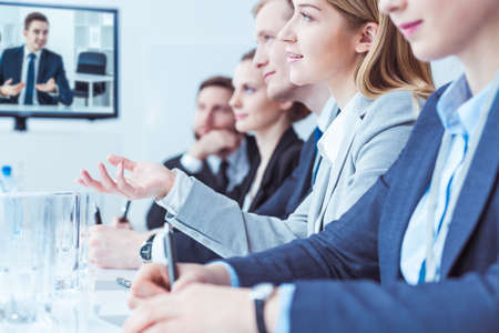 Close-up of conference participants sitting in a row at a conference table, a young woman asking questionsの写真素材