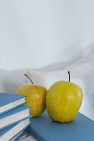 Shot of apples standing on the books with blue covers facing a white wallの写真素材