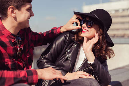 Man with checked, hipster shirt needling the woman with glasses, black hat and leather jacketの写真素材