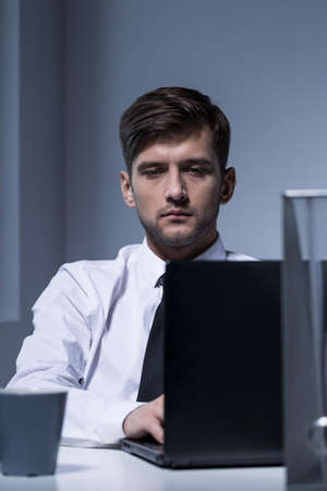 Cropped shot of a tired man working in the office with his laptopの写真素材