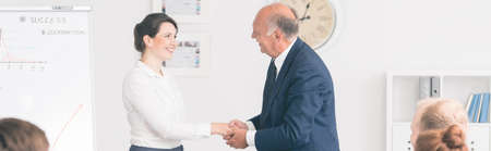 Panoramic picture of a boss shaking hands with a young businesswoman