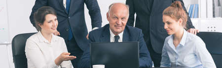 Shot of a group of workers having a meeting and using a laptopの写真素材