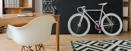 Shot of a cozy interior with a white chair and a bike against a blackboard wallの写真素材