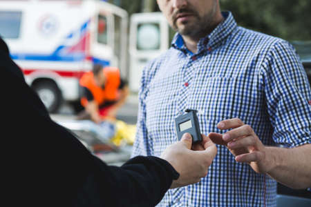 Police officer giving the breathalyser to the other man