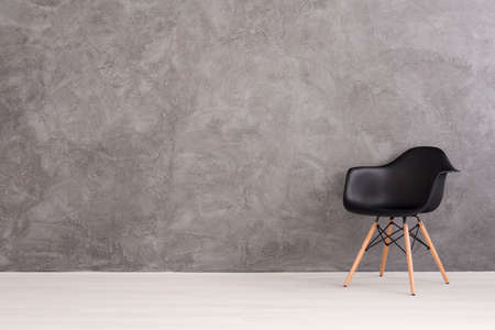 Black plastic chair on a background of a gray concrete wallの写真素材