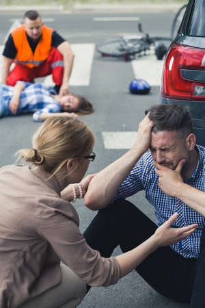 Crying man sitting on the street with the rescue action behind him