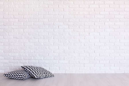 Two pillows in geometric pattern on the background of a white brick wallの写真素材
