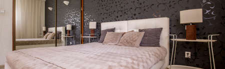 Panoramic shot of a luxury bed and a sliding wardrobe with a mirror