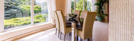 Panoramic view of a dining area with a large window and rectangular tableの写真素材
