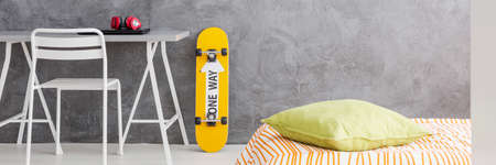 Orange skateboard leaning on a grey stucco wall of modern bedroomの写真素材