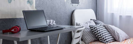 Close-up of a grey desk and bed in a contemporary bedroomの写真素材