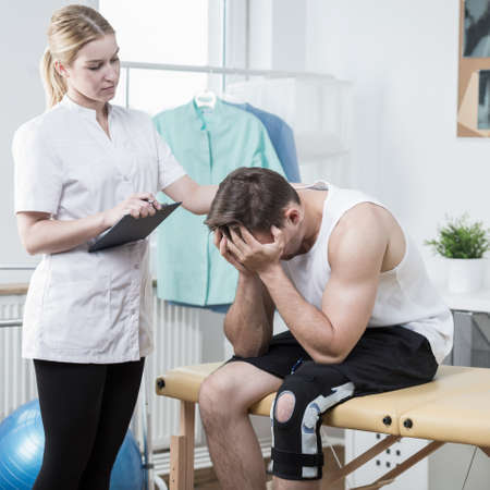 Physical therapist is consoling young injured patientの写真素材