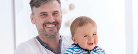 Happy father holding his small smiling son, panorama