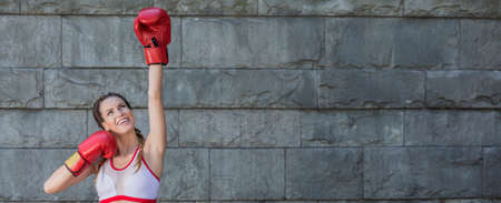 Panoramic picture of a smiling young boxer against a concrete wall outdoorsの写真素材