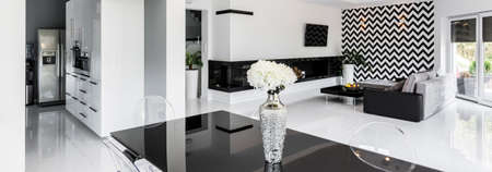 Closeup shot of a vase with flowers standing in the middle of a black dining tableの写真素材