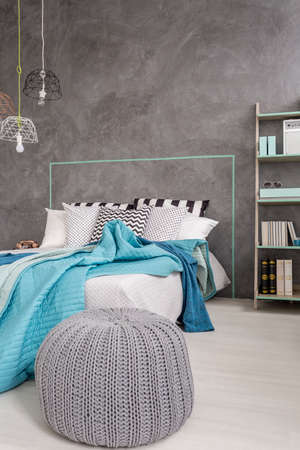 Grey bedroom with comfortable pouf, bed, and decorative wall finish