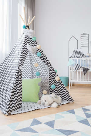 Bright baby room interior with a teepee and teddy bearの写真素材