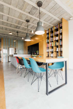 Spacious dining room linked with kitchen in a very modern apartment with concrete ceiling