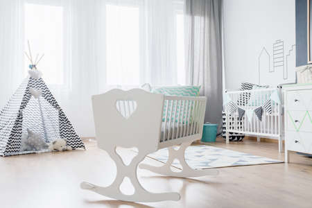 Bright baby room with stylish cradle and teepee with soft toys