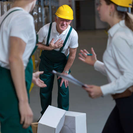 Senior storage worker having heart infarct in warehouseの写真素材