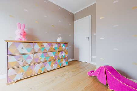 Little girl's room with a wonderful hand-decorated chest of drawers, white door and a pink pouffe in the shape of a wiener dogの写真素材