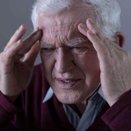 Elderly man holding his head with terrible pain