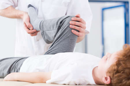 Boy during physiotherapy exercising with professional therapist