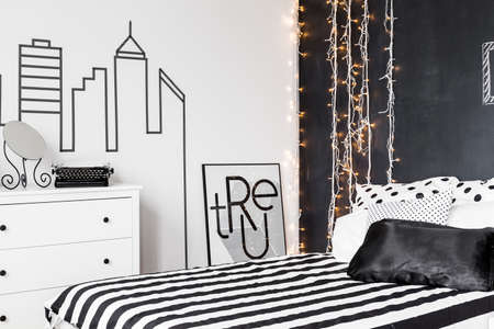 Bedroom with a bed and white commode with the mirror on itの写真素材