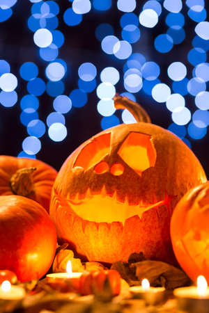 Shot of a Halloween pumpkin with a carved face standing against a background of lightsの写真素材