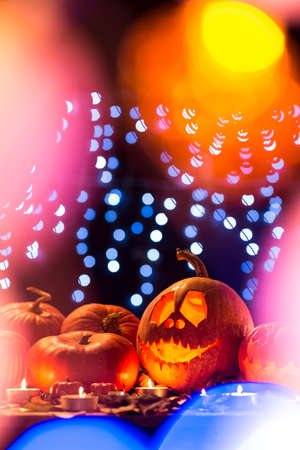 Shot of a Halloween pumpkins standing on a table with a lighting in the backgroundの写真素材