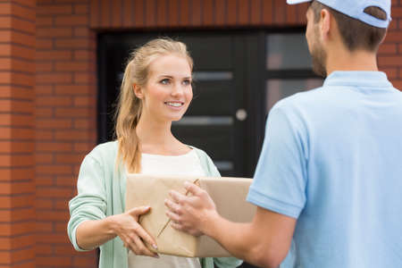 Smiled, blonde woman receiving the delivery from the post manの写真素材