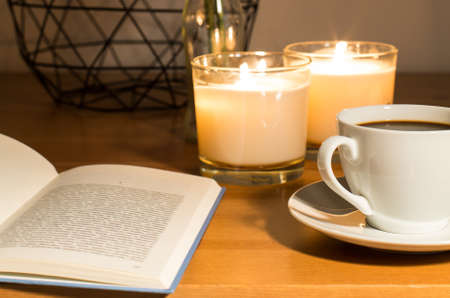 Tabletop with open book, candles, cup of coffee and geometric decorative bowlの写真素材
