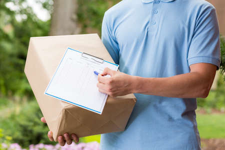 Closer shot of a postman keeping the package and delivery sheet