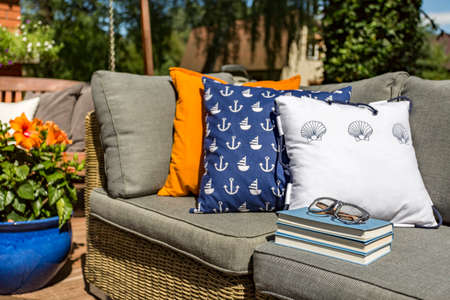 Image of pattern pillows lying on a rattan outdoor sofaの写真素材