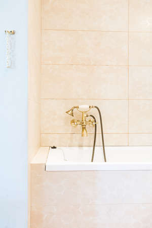 Close shot of a bathroom with a bathtub with golden tap and shower head